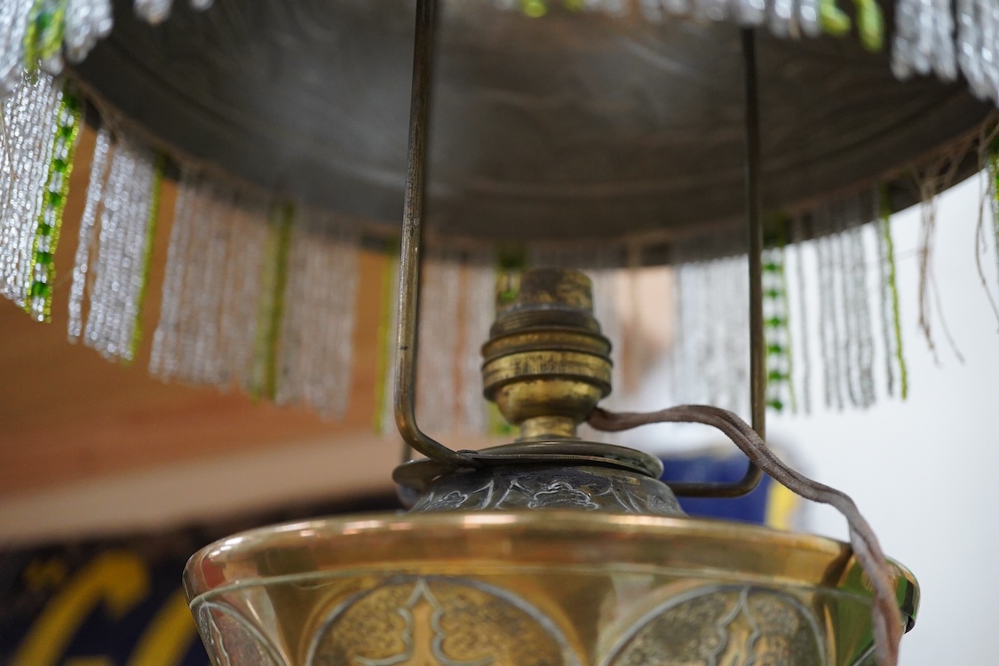 After Georges Leleu, an Art Nouveau brass oil lamp converted to electricity, with glass cabochon roundels and beaded fringing, 50cm high